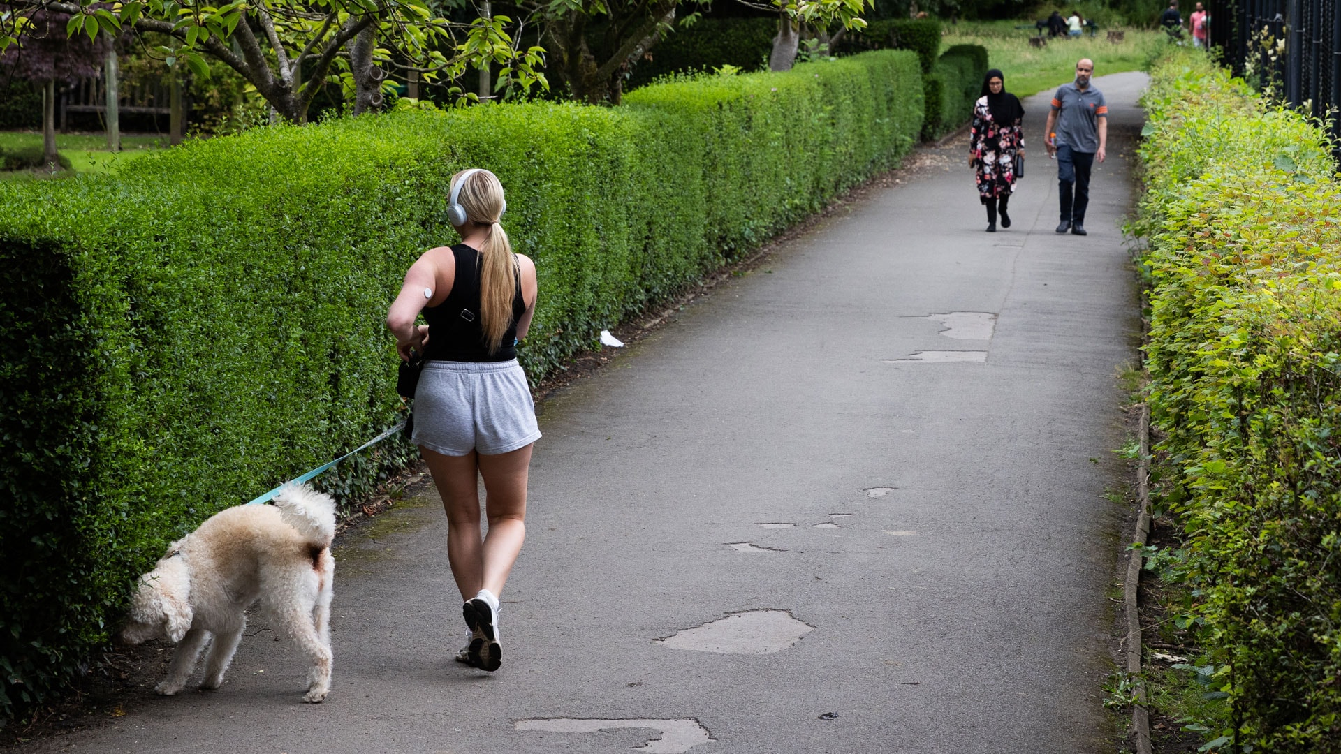 A footpath in Fletcher Moss Gardens, Manchester with people walking and a dog on a lead